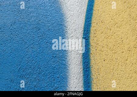 Texture of rough plastered wall painted blue, yellow and white. Scratched concrete outdoor wall. Colored grunge cement surface. Abstract background. Stock Photo