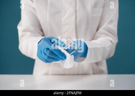 Nurse in dressing gown carries out disinfection by wiping off protective goggles Stock Photo