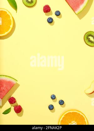 various fresh fruit slices and berries on yellow background, top view Stock Photo