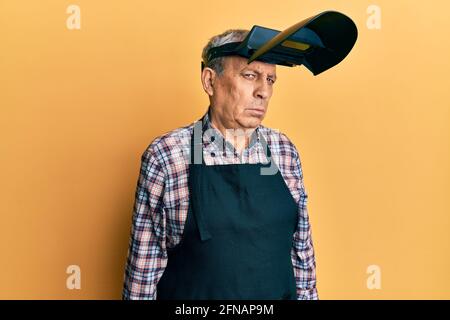 Handsome senior man with grey hair wearing welding protection mask depressed and worry for distress, crying angry and afraid. sad expression. Stock Photo