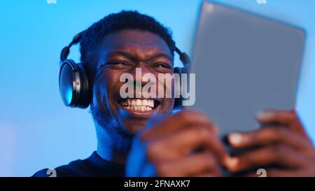 African american black man with headphones making intense face expressions while using tablet. High quality photo Stock Photo