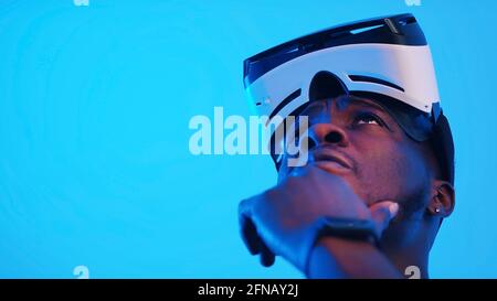 Pensive African-American guy with virtual reality glasses on his forehead looking around. High quality photo Stock Photo
