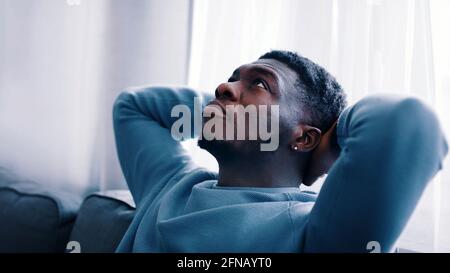 Serious man thinking while sitting on a blue sofa - Hands behind the head . High quality photo Stock Photo
