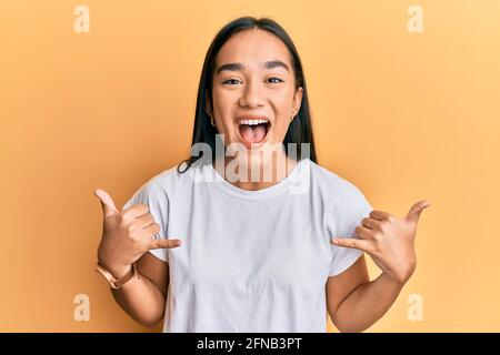 Young asian woman doing shaka sign with hands smiling and laughing hard out loud because funny crazy joke. Stock Photo