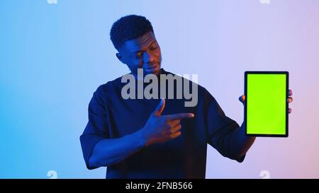 African american black man holding a digital tablet with a green screen pointing at the tablet. High quality photo Stock Photo
