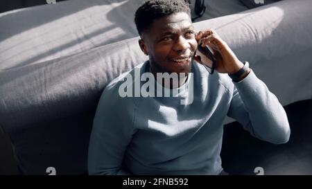 African-American man sitting on the floor talking to someone on his phone. High quality photo Stock Photo