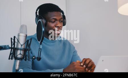 Man wearing headphones recording a video podcast using a laptop and microphone. High quality photo Stock Photo
