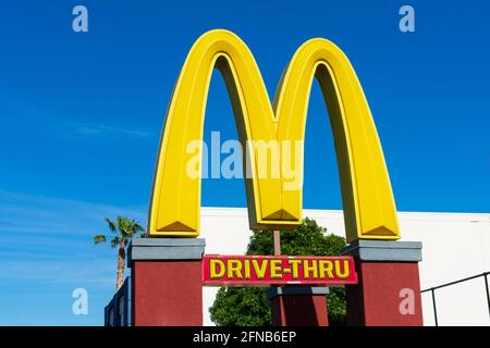 McDonald's Golden Arches symbol. Drive thru sign at fast food chain restaurant location under blue sky. Close up - Santa Clara, California, USA - 2021 Stock Photo