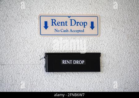 Rent Drop, No cash accepted sign with down arrow pointing to flap of secure rent drop box on the wall Stock Photo