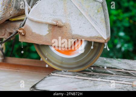 Construction works tiling with a circular saw a man sawing ceramic tiles worker sawing a tile Stock Photo