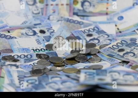 A pile of one thousand Philippines banknotes and coins Stock Photo