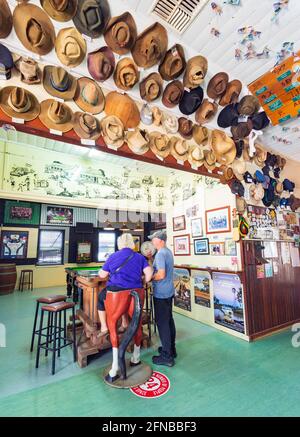 Tourist sitting on an amusing bar stool at the popular rural Wellshot Hotel, Ilfracombe, Central Queensland, QLD, Australia Stock Photo