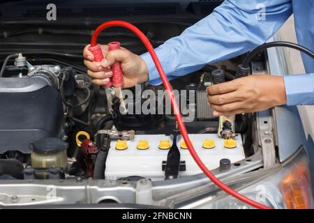businessman using jumper cables to start a car in parking lot Stock Photo