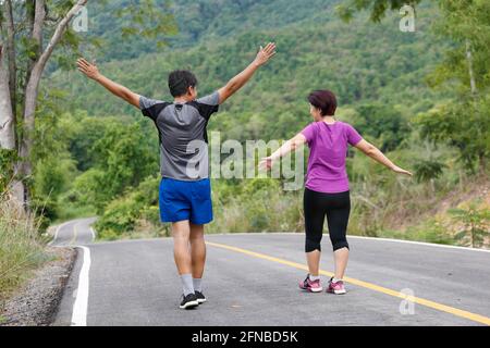 Asian middle aged couple stretching muscles before jogging in park Stock Photo