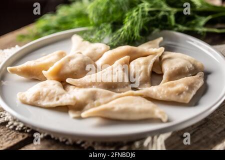 Freshly cooked pierogi or vareniki dumplings with filling but without a topping served on a plate. Stock Photo