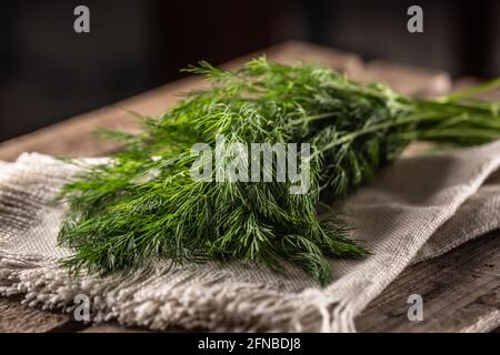 Fresh dill on a linen cloth and wooden surface. Stock Photo