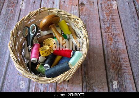 Different sewing items in wicker basket on wooden background Stock Photo