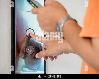 The finger of male pressing the elevator or lift button for next level up in apartment or condominium. More advance to success concept. Stock Photo