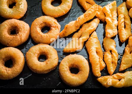 Closeup of golden donuts on black tray. Homemade pastries. Donuts for Fat Thursday. Stock Photo