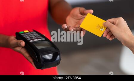 Closeup of black delivery man in uniform holding POS machine Stock Photo