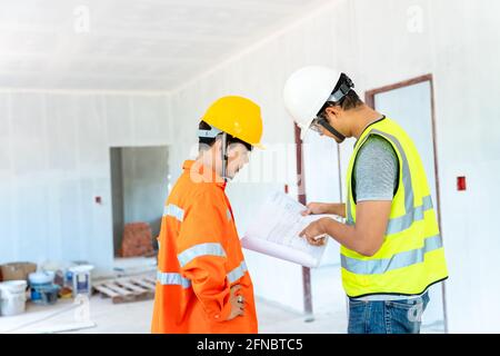 Asian architect and engineer fiving instructions to his foreman on clipboard working at construction site Stock Photo