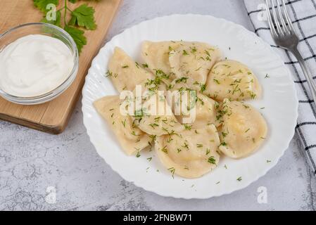Ukrainian dumplings - dumplings with potatoes and sour cream with dill Stock Photo