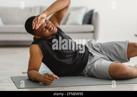 African American Guy Feeling Bad During Workout At Home Stock Photo