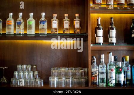 Soft focus shot of wooden shelf in a bar pub hotel filled with liqor bottles from top brands of whiskey, gin, rum, vodka and more Stock Photo