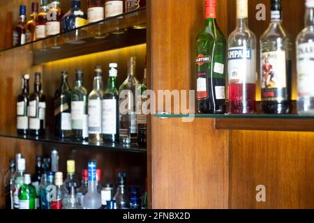 Soft focus shot of wooden shelf in a bar pub hotel filled with liqor bottles from top brands of whiskey, gin, rum, vodka and more Stock Photo