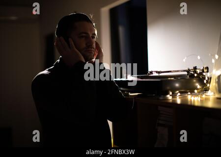 Young unshaven handsome millennial guy focused on music with headphones Stock Photo
