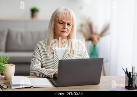 Mature woman sitting ot desk and working on computer Stock Photo