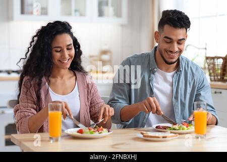 Couple's Daily Life. Happy middle eastern spouses eating breakfast in kitchen Stock Photo