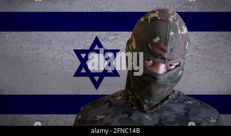 Militant israel angry soldier with green camouflage balaclava on israeli flag. Military Zionist fighter ready for occupation battle with star david be Stock Photo