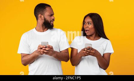 Confused sad millennial african american couple holding their phones Stock Photo