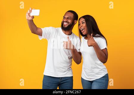 Happy black man and woman taking selfie showing thumbs up Stock Photo