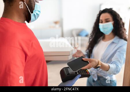 Black man holding POS machine client paying with smartphone Stock Photo