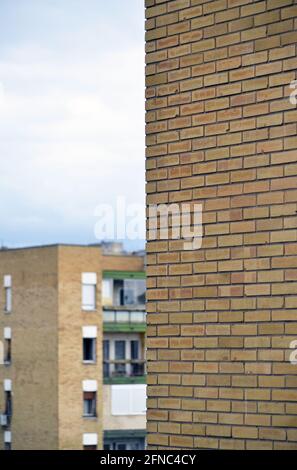 a light brown clay bricks building facade with a detail of another building and blue cloudy sky in background Stock Photo