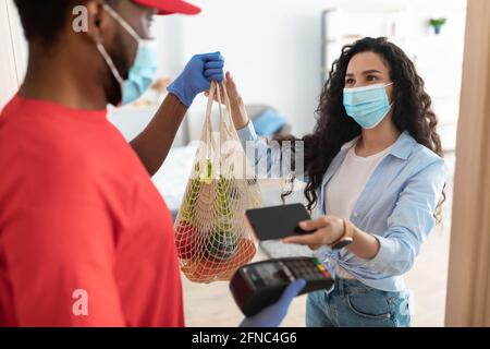 Black delivery man holding POS machine for payment Stock Photo