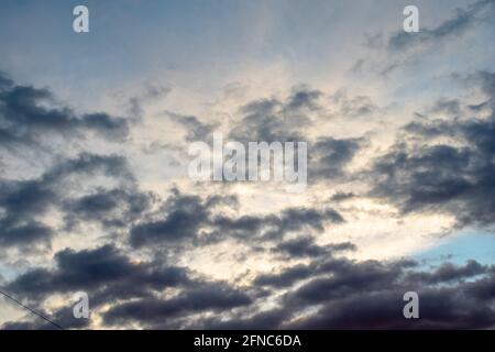 Background of dark clouds before a thunder-storm. Dramatically illuminated clouds in the evening sky. Stock Photo