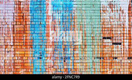Brick wall with multi-colored drips of paint. Stock Photo