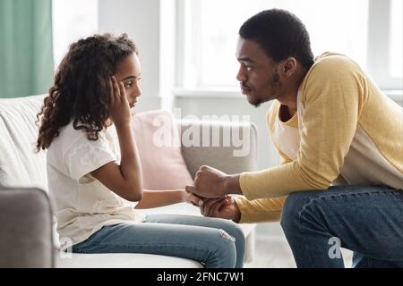 Black father comforting his upset kid, home interior Stock Photo
