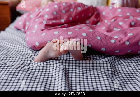 baby feet sticking out from under the blanket. children's recreation Stock Photo