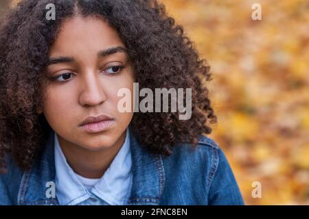 Beautiful mixed race African American girl teenager female young woman outside looking sad depressed or thoughtful, mental health concept Stock Photo