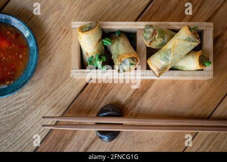 Vietnamese spring rolls with sweet sauce. Fried chinese spring rolls with sweet chili sauce. Asian appetizers or snacks. Asian cuisine. Rolls beautifully served in decorative wooden boxes. Stock Photo