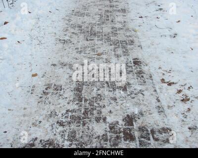 A tiled path in a snow-covered park Stock Photo
