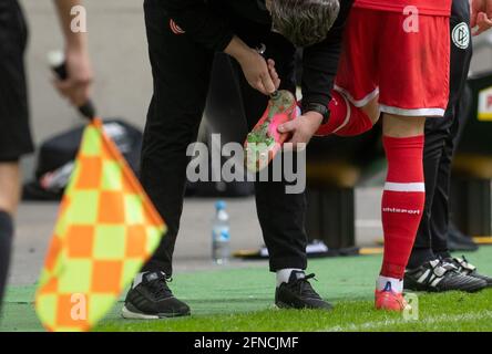 Duesseldorf, Germany. 16th May, 2021. Football: 2. Bundesliga, Fortuna Düsseldorf - Erzgebirge Aue, 33. matchday at Merkus Spiel-Arena: A coach tightens the studs on the shoes of Düsseldorf's midfielder Felix Klaus. Credit: Bernd Thissen/dpa - IMPORTANT NOTE: In accordance with the regulations of the DFL Deutsche Fußball Liga and/or the DFB Deutscher Fußball-Bund, it is prohibited to use or have used photographs taken in the stadium and/or of the match in the form of sequence pictures and/or video-like photo series./dpa/Alamy Live News Stock Photo
