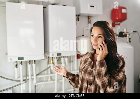 Young woman with smartphone by ear calling repairman Stock Photo