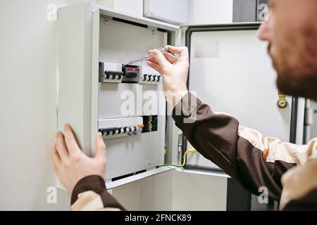 Young plumber in uniform doing repair work in large modern house Stock Photo