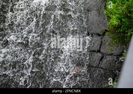 water flowing over black stones of a weir Stock Photo