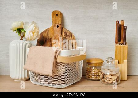 Two wooden chopping boards and towels in a basket next to a vase of flowers Stock Photo